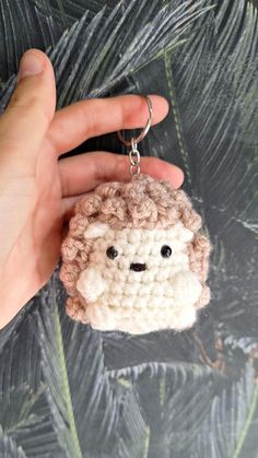 a hand holding a keychain with a small sheep on it's face