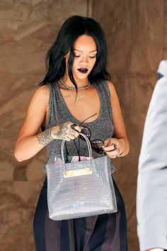 a woman with black hair is carrying a gray purse