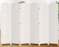 a white room divider sitting on top of a hard wood floor next to a potted plant