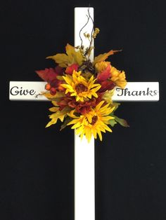 a cross decorated with sunflowers and leaves is shown in front of a black background