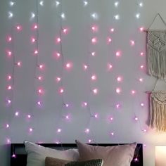 a bed with pink lights hanging from it's headboard next to a night stand