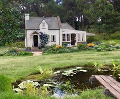 a white house sitting on top of a lush green field next to a small pond