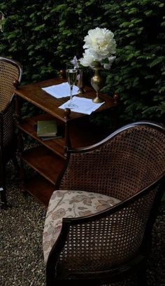 two wicker chairs sitting next to each other near a table with flowers on it