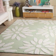 a green rug with white flowers on it in front of a couch and coffee table