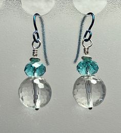 These sparkling earrings feature 12 mm faceted crystal quartz beads and 8 x 5 mm faceted aqua-blue Swarovski crystals. The findings are all sterling silver and the ear wires are blue hypoallergenic niobium. (If you prefer sterling silver ear wires, I'd be happy to change them.) The earrings measure 1-1/2 inches from the top of the ear wire to the base of the earring.  **All Spritely Finch Jewelry is gift boxed and shipped by first class mail with delivery confirmation (plus insurance if the value is greater than $75).** All proceeds will be donated to the Daisy Fund (helping needy pet owners with veterinary expenses) at the Palo Alto Humane Society (PAHS): http://www.paloaltohumane.org/ Silver Crystal Earrings With Gemstones, Round Crystal Gemstone Earrings, Silver Faceted Round Crystal Earrings, Silver Faceted Crystal Earrings, Round Crystal Earrings With Faceted Beads, Nickel-free Clear Round Crystal Earrings, Faceted Crystal Dangle Earrings, Faceted Clear Crystal Earrings Gift, Silver Crystal Earrings With Faceted Beads