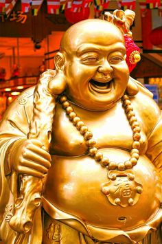 a statue of a laughing buddha with beads on it's neck and hands in the air