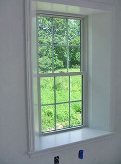 a window in the corner of a room with white walls and windowsills on each side