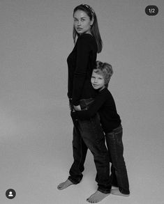 two young children standing next to each other in front of a gray background with black and white images