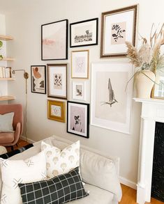 a living room filled with furniture and framed pictures on the wall above it's fireplace