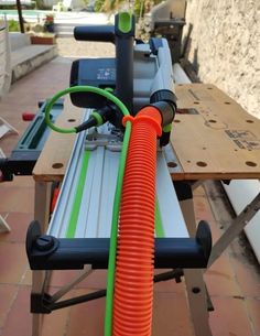 an orange hose is attached to the handle of a machine on a wooden table outside