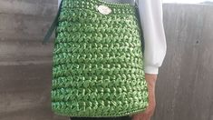 a woman is holding a green crocheted purse