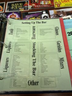 a menu sitting on top of a wooden table next to a pile of books and magazines