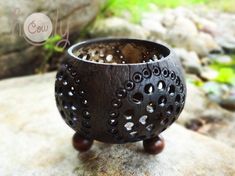 a wooden candle holder sitting on top of a rock next to some plants and rocks