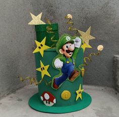 a green and gold cake with mario running on it's side, surrounded by stars