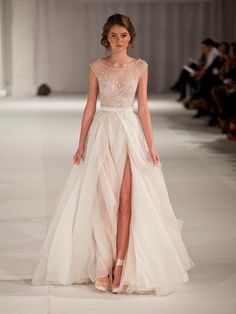 a woman is walking down the runway in a white dress