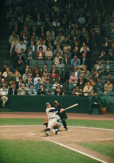 a baseball player holding a bat on top of a field in front of a crowd