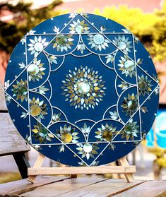 a decorative blue plate sitting on top of a wooden table next to a park bench