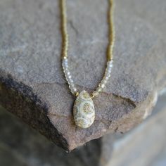 A fossil coral teardrop with nice pattern is combined with microfaceted golden natural zircon beads, 22k gold vermeil accents, and  golden glass seed beads, all strung on silk to give the necklace a nice drape on the neck.   17 inches 14k gold fill clasp Gold Teardrop Drop Necklace With Natural Stones, Bohemian Gold Teardrop Pendant Drop Necklace, Gold Bohemian Teardrop Pendant Drop Necklace, Bohemian Gold Teardrop Pendant Necklace, Gold Teardrop Faceted Beads Jewelry, Gold Teardrop Necklace With Gemstone Beads, Gold Teardrop Jewelry With Faceted Beads, Gold Oval Beaded Necklace With Tiny Beads, Gold Drop Bohemian Necklace