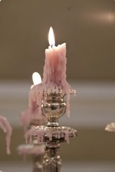 a candle that is sitting on top of a metal stand with pink icing around it