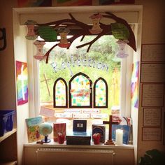 an open window with stained glass and artwork on the windowsill in front of it