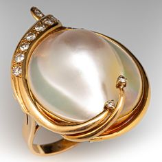 This gorgeous 18k yellow gold ring is centered with one (1) blister pearl set into a bezel. Two ribbons of yellow gold that extend over the blister pearl are accented with two (2) prong set round brilliant cut diamonds. The blister pearl is bordered with ten (10) bead set round single cut diamond accents. The ring measures 33.9mm at the top, rises 3.9mm above the finger, and tapers to 2.8mm wide by 1.0mm thick at the base of the shank.  The ring is currently a size 6.75. Pearl Necklace Vintage, Pearl Necklaces, Vintage Pearl, Pearl Collection, Bead Set, 18k Yellow Gold Ring, Pearl Set, Vintage Pearls, Yellow Gold Ring