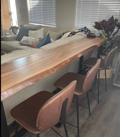 a long wooden table with four chairs next to it and a couch in the background