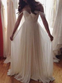 a woman standing in front of a mirror wearing a white dress