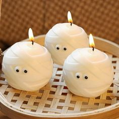 three candles with faces on them sitting in a basket