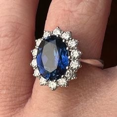 a woman's engagement ring with a blue and white stone surrounded by small diamonds