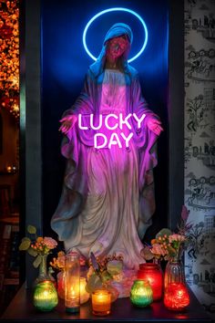 a neon sign that says lucky day in front of a statue with flowers and candles