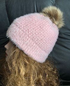 a pink knitted hat with two pom - poms sitting on top of a mannequin head