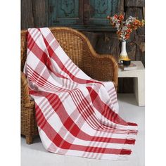 a red and white checkered blanket sitting on top of a chair next to a vase