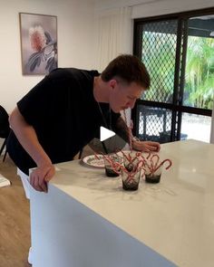 a man standing over a counter with candy canes