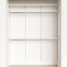 an empty closet with white shelving and wood flooring