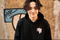 a young man standing in front of a wall with graffiti and palm trees on it