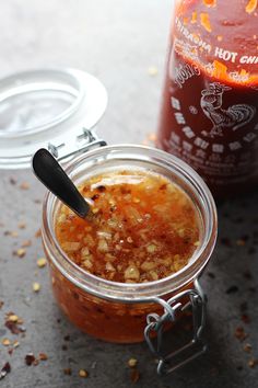 a jar filled with food sitting on top of a table next to a bottle of sauce