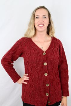 a woman wearing a red sweater and black pants with her hands on her hips, smiling at the camera