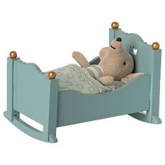 a teddy bear laying in a blue wooden bed