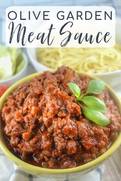 a yellow bowl filled with meat sauce next to pasta and lettuce on the side