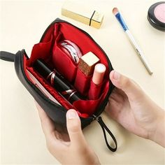 a person holding an open makeup bag on top of a table