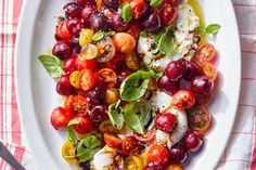 a white plate topped with tomatoes and mozzarella next to a fork on a red checkered table cloth