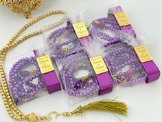 purple and gold bracelets with tags on them sitting next to a golden beaded necklace