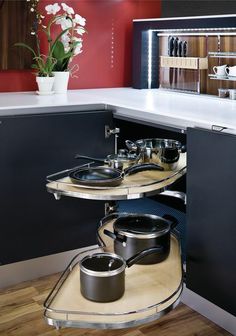 a kitchen with black cabinets and white counter tops is pictured in this image, there are pots on the shelf