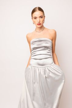 An exquisite maxi dress with a bandeau style that will elevate your fashion game. The dress features a beautiful two tone fabric detail and a flattering drop waist that accentuates your figure. The ruche effect on top adds a touch of elegance, while the full maxi skirt adds a flowy and feminine touch to the overall look. 97% Polyester, 3% Elastane Hand wash Silver Maxi Dress, Metallic Trousers, Full Maxi Skirt, Drop Waist Dress, Satin Maxi, Satin Maxi Dress, Dropwaist Dress, Halterneck Dress, Style Maxi Dress