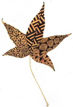 an artistically designed wooden star on a stick with geometric patterns and lines, against a white background