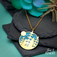 This Moon and Pine Tree Pendant Necklace is a beautiful gift for those enchanted with nature! This necklace Pendant features a Brass cutout component and a Brass disk that has been carefully handmade and painted in our studio. Trees are symbols of strength, individuality and expression. The sun represents life but it's also known to typify energy, power, positivity, and clarity.The Moon represents your fears and illusions and often comes out when you are projecting fear into your present and you Handmade Moon Shaped Nature-inspired Necklace, Nature-inspired Round Pendant Jewelry With Moon Charm, Nature-inspired Moon Charm Jewelry As A Gift, Nature-inspired Moon Charm Necklace As A Gift, Nature-inspired Moon Charm Necklace As Gift, Nature-inspired Moon Charm Necklace For Gift, Dangle Necklace, Symbols Of Strength, Night Landscape