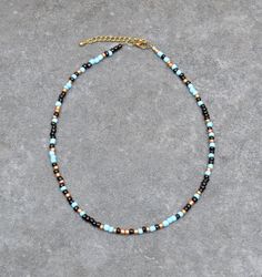 Cheerful seed bead necklace with irregular 4 mm beads. The length can be adjusted with 2 inches (5 cm). The colors of the beads are matte light blue and black. The bronze beads in between give the necklace an elegant sparkle.  A perfect necklace to cheer up a plain outfit. Also eye catching to wear a few of them together in different lengths. The necklace is finished with a Designer Quality brass clasp and findings Here you find my shop: https://MacchiatoSoul.etsy.com * Macchiato Soul offers uni Turquoise Beaded Necklaces With Black Beads For Festival, Blue And Black Beads Bohemian Necklace, Blue Necklaces With Black Beads For Festival, Blue Necklace With Black Beads For Festival, Bohemian Blue And Black Beaded Necklaces, Artisan Blue Beaded Necklace With Tiny Beads, Artisan Blue Heishi Beaded Necklaces, Artisan Blue Heishi Beads Necklace, Southwestern Blue Beaded Necklace With Tiny Beads