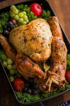 a close up of a chicken on a plate with grapes and broccoli in the background