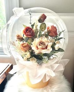 a vase filled with flowers sitting on top of a white fur covered table next to a window