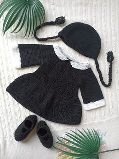 a knitted black and white outfit with matching hat, booties and palm leaf